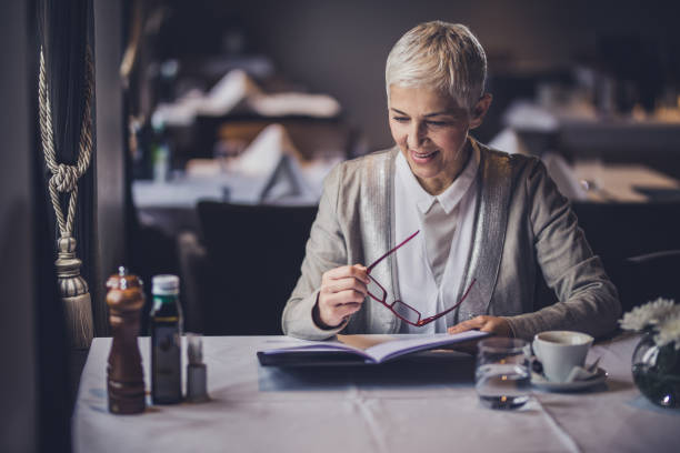 Happy mature woman reading Menu in a restaurant.
