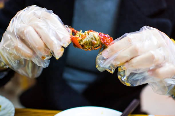 istock Woman eating a crayfish with plastic gloves 909419710