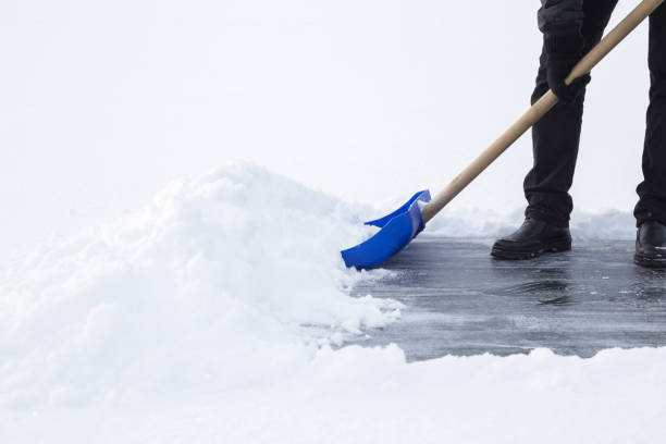 istock Man cleaning snow with blue shovel from ice surface for ice skating. Winter routine concept. 909420562