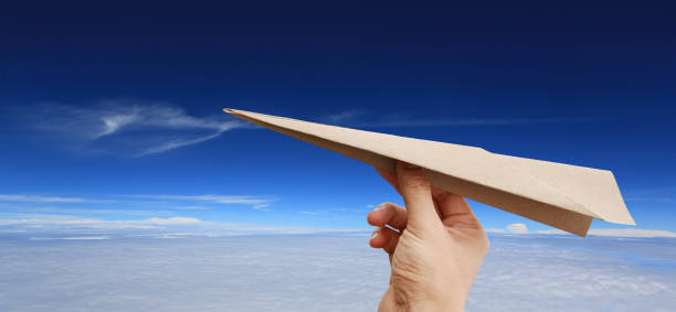 istock Brown aircraft rocket paper in hand on puffy cloud sky background. 909423024
