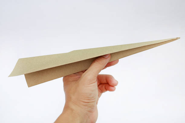 istock Brown aircraft paper in hand on white background. 909423482