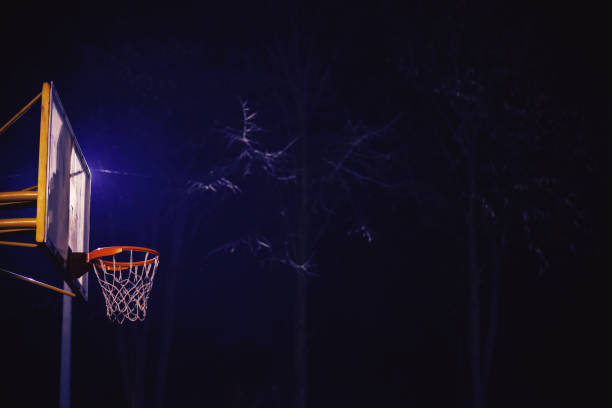 Emtpy basketball court by night, details of hoop and terrain.