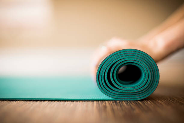 Woman rolling up yoga mat. Yoga training concept. mat stock pictures, royalty-free photos & images