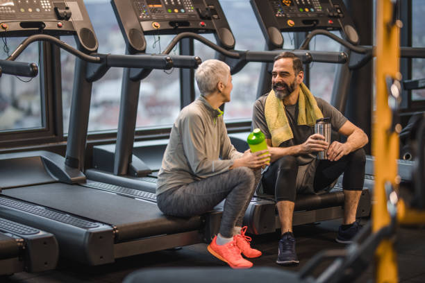 istock Smiling senior couple talking while having a break from sports training in a gym. 909424130