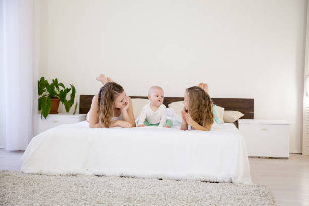 три девочки играют сестры утром на кровати в спальне - three objects men three people brother стоковые фото и изображения