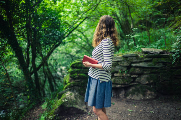 istock Woman with book standing in the forest 909424838
