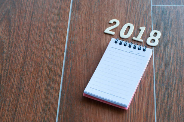 istock notepad with pencil, backboard and number 2018 on wood backgorund for happy new year image. And welcome new year photo. 909428100