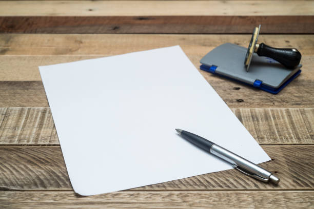 istock pen on whitepaper with stamper on wooden background. 909431594