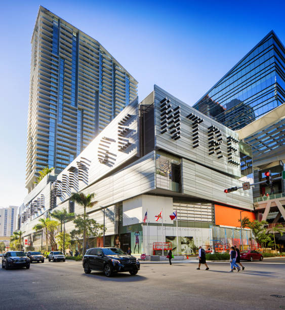 Miami Brickell City Centre building corner view lit by sunset with light traffic and a few pedestrians crossing the street.