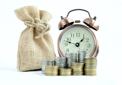 Saving money ,Economizing which have pile of coins ,Clock and money bag on white background. Currency , Investment fund , Business and Money Concept.