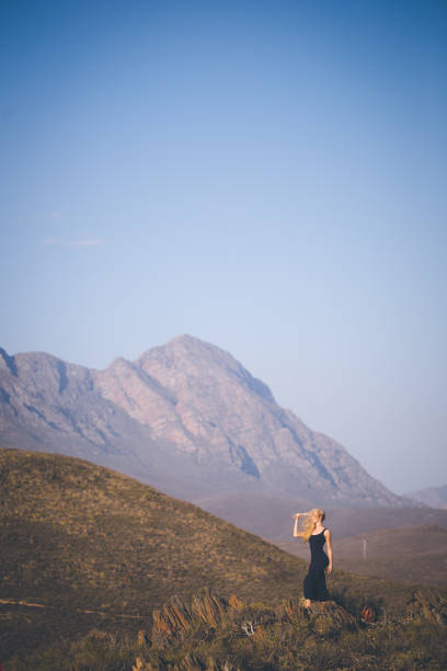 istock Beautiful blond female model standing on a mountain enjoying the view 909436576