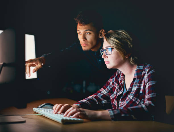 istock Man points out something on PC at night to woman 909436912