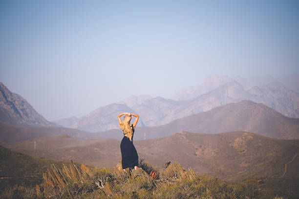 istock Beautiful blond female model standing on a mountain enjoying the view 909436966