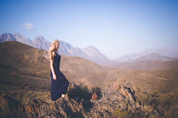 istock Beautiful blond female model standing on a mountain enjoying the view 909437108