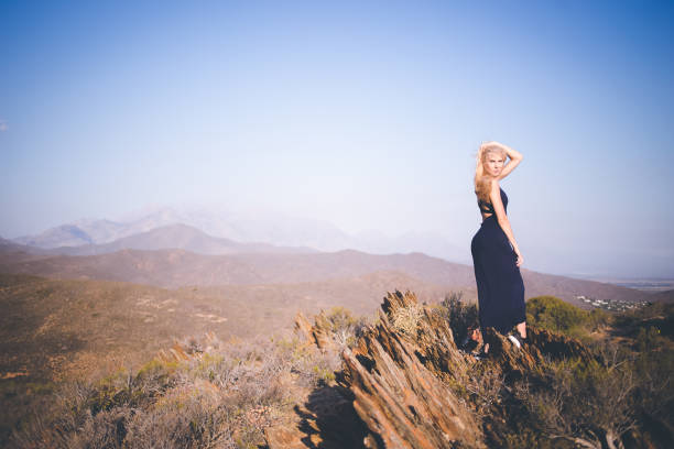 istock Beautiful blond female model standing on a mountain enjoying the view 909437148