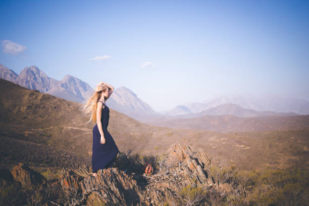 istock Beautiful blond female model standing on a mountain enjoying the view 909437252