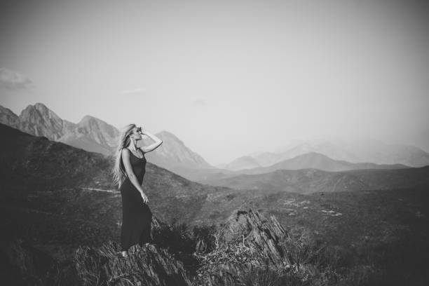 istock Beautiful blond female model standing on a mountain enjoying the view 909437300