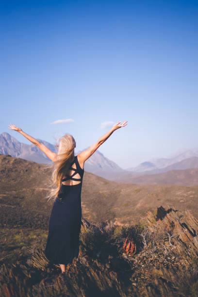istock Beautiful blond female model standing on a mountain enjoying the view 909437428