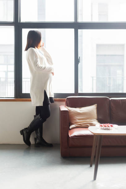 istock pregnant woman talking on phone by window 909439742