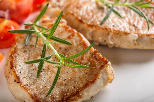 istock Fried pieces of pork chop with roasted vegetables on plate 909441940