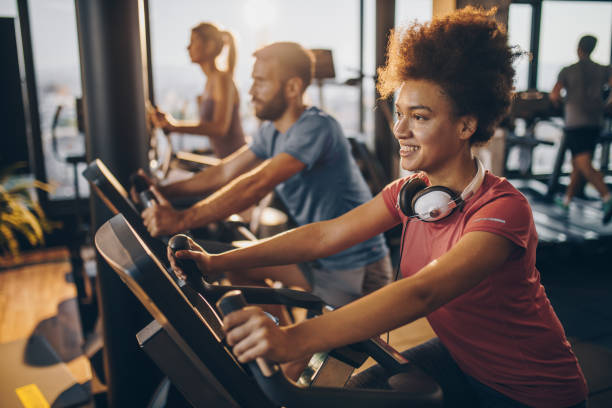 happy black athlete practicing on exercise bike in a health club. - bicycle women cycling gym imagens e fotografias de stock