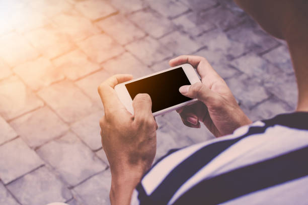 istock Close up of men hands holding touching mobile phone with blank copy space for your text message in cafe with light Sunset,Vintage tone.Selective focus 909444274