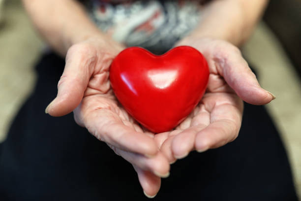 istock elder woman holding heart 909445388