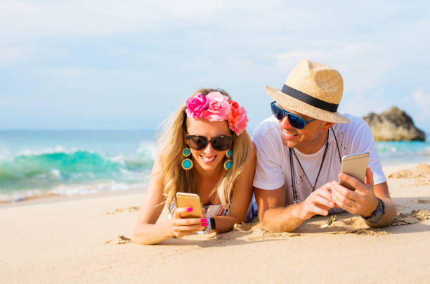 istock Couple lying on the beach and using mobile phones 909446378