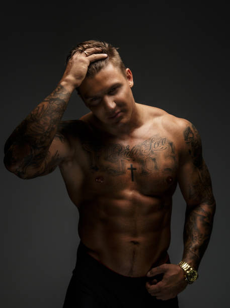 istock Muscular man with tattooes in deep shadows 909449386