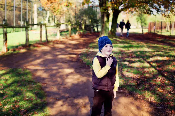 A cheerful little boy having fun in a park on sunny autumn day, November 2014, United Kingdom.