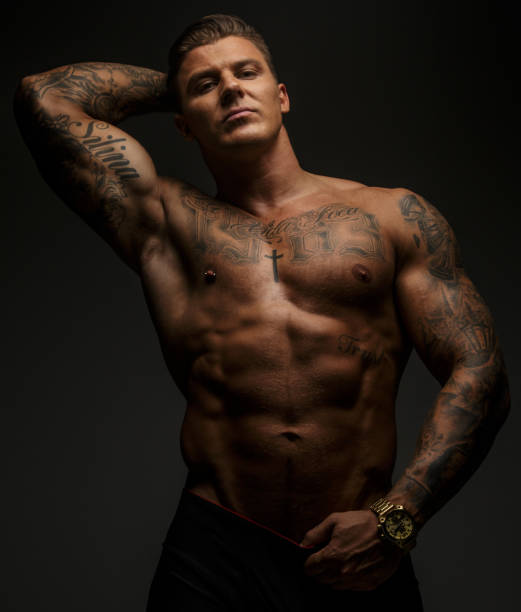 istock Tattooed muscular guy posing on gray background 909456944