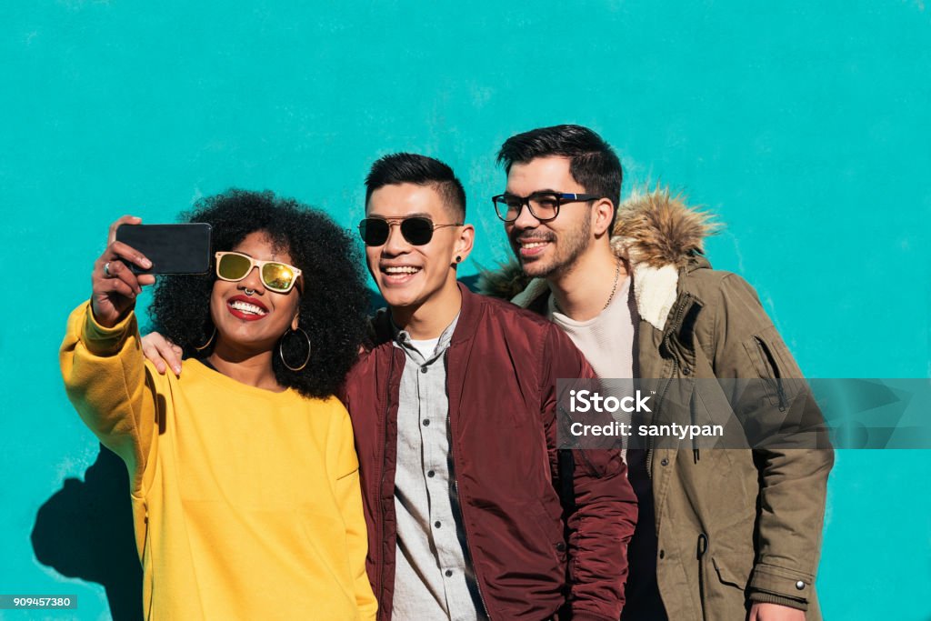 Group of happy friends taking a selfie in the street. Group of happy friends taking a selfie in the street. Friendship concept. Three People Stock Photo