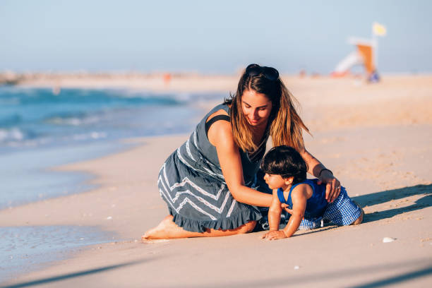 istock baby boy playing on the shoreline with mom 909460824