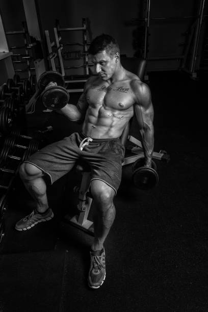 istock Hot bodybuilder is bulding up his biceps 909460954