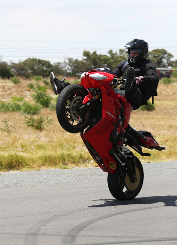 Cape Town, South Africa, January 21, 2018:  Motorbike riders from the club “Cape Town Supermotard Street Legal” practice their stunts along Link Road, Montague Gardens, which is a public road in the suburb.