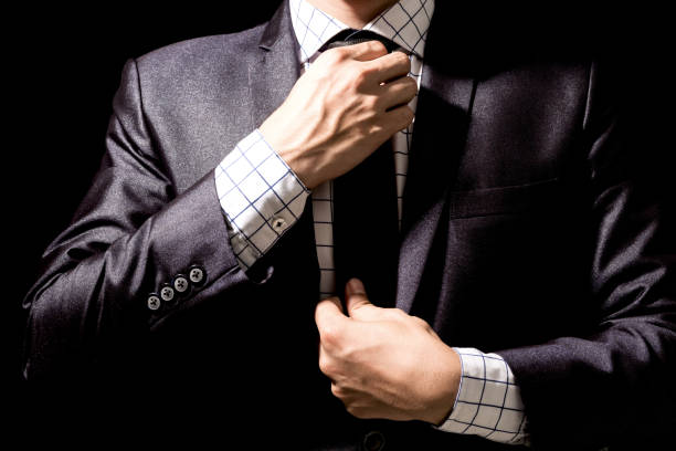istock Businessman adjusting his suit on black background 909461926