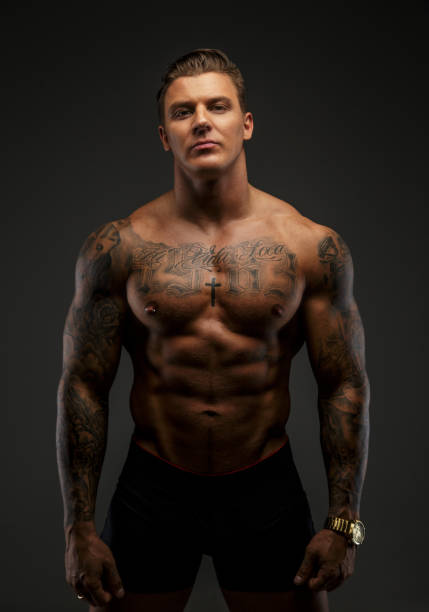 istock Muscular man with tattooes in deep shadows 909462192