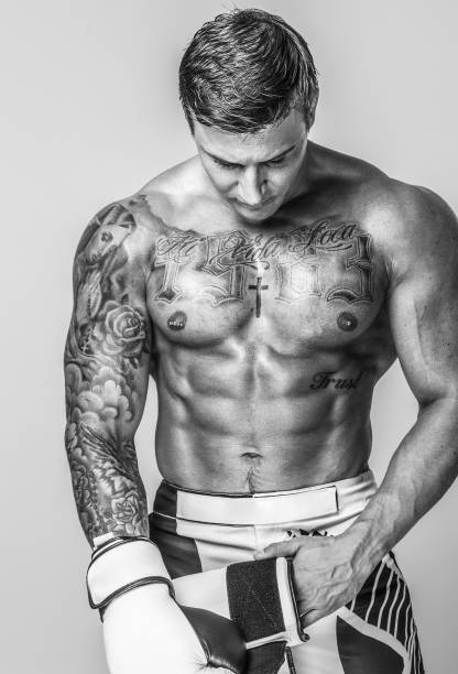 istock A muscled and tattooed man is putting on boxing gloves 909462388