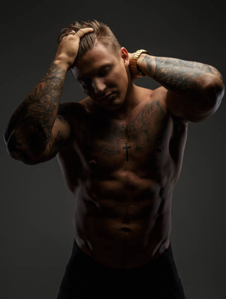istock Muscular man with tattooes in deep shadows 909463296
