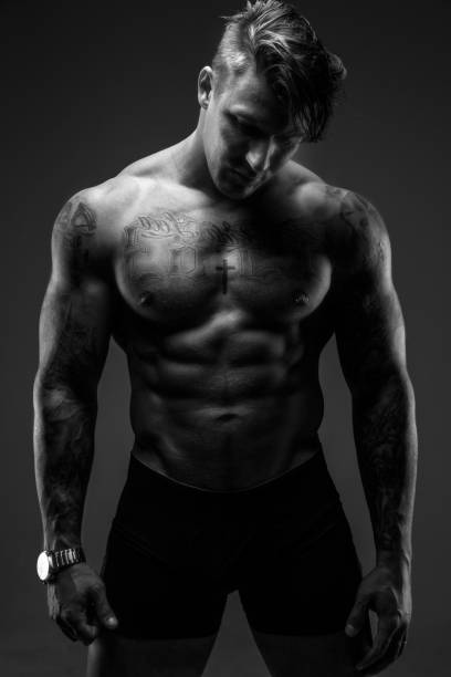istock Muscular man with tattooes in deep shadows 909468274