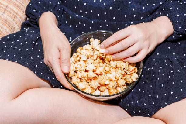 istock Woman eating popcorn on sofa 909469402