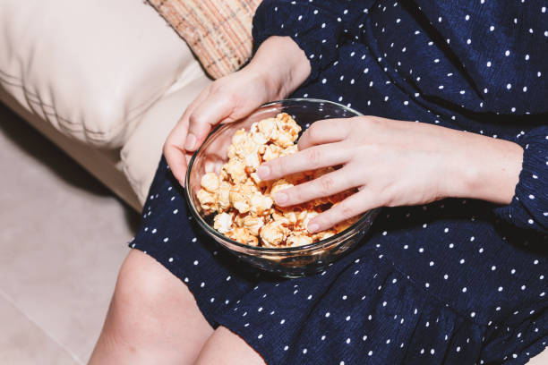 istock Woman eating popcorn on sofa 909469404