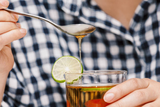 istock Woman hand add honey into lemon tea 909475062