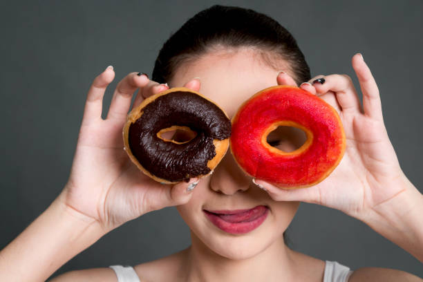 istock Woman holding donut on eye on gray background 909475104