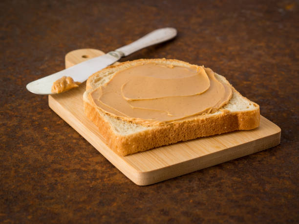 istock Peanut Butter on Toast. Old rusty metal dark background, side view, selective focus 909475176