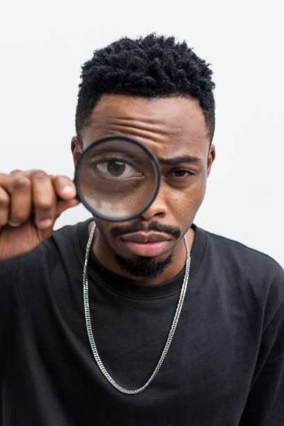 istock African man playing with a magnifying glass 909475208
