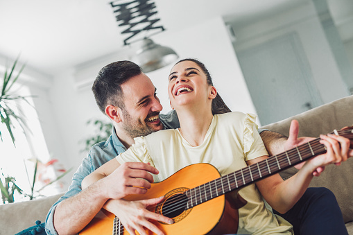 Loving couple with guitar in the room at home