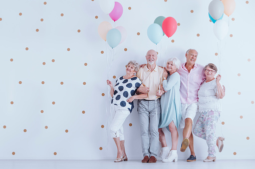 Happy older people smiling and standing with colorful balloons at the New Year's Eve party photo