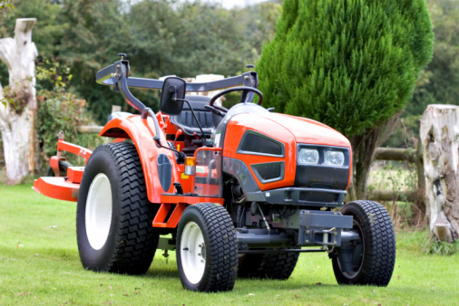 Compact tractor with a mowing deck on the back. Roll bar is down so that it can mow under the apple trees!