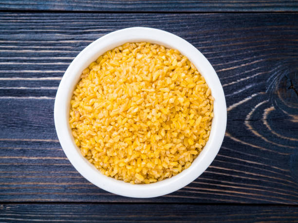 istock White bowl  with raw bulgur on dark brown wooden background. Top view. 909481184